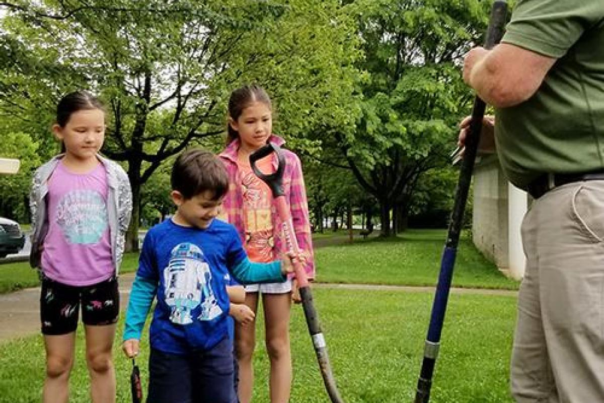 Jim Carpenter invites the children to help shovel dirt around the post.